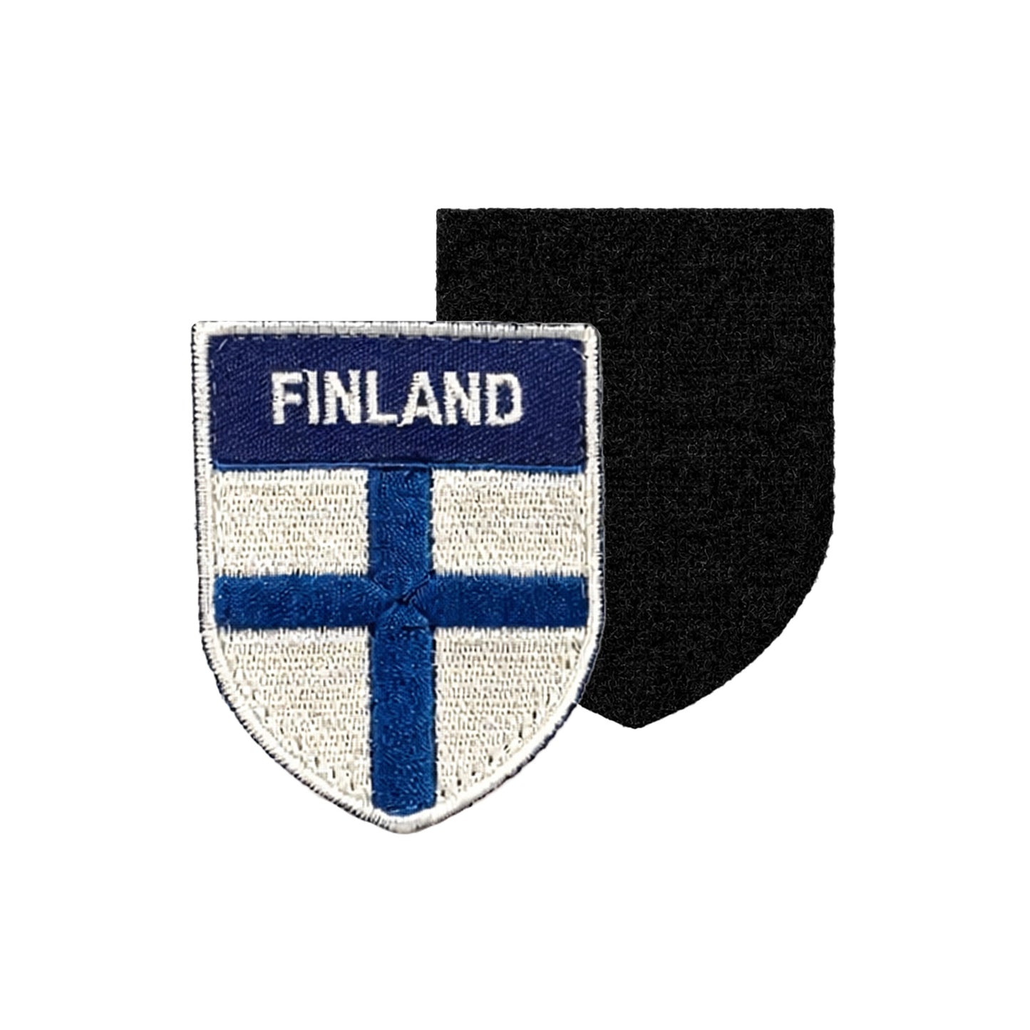Broderat märke i sköldformat med vit bakgrund, blå finsk flagga och texten “FINLAND” i vitt på blå överdel, samt svart kardborrebaksida för enkel fastsättning