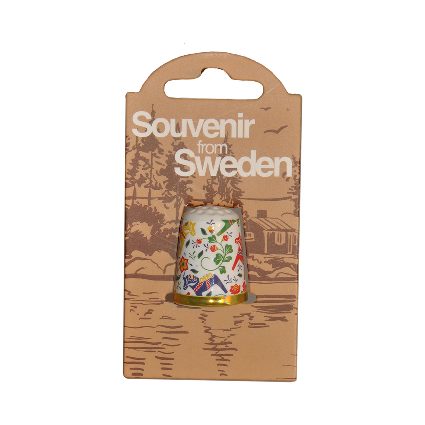 Forpackning med fingerborg med motiv av färgglada dalahästar. På förpackningen står det "Souvenir from Sweden".
