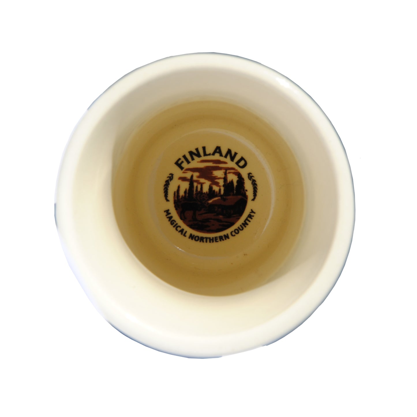 Shotglas i keramik fotat uppifrån med crémefärgad insida, skogsmotiv och texten 'Finland Magical Northern Country' i botten.