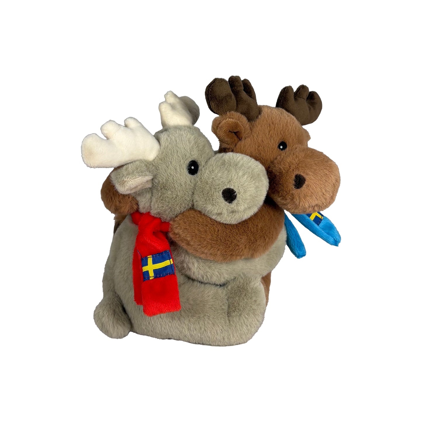 Två gosedjursälgar som kramas, en grå med iklädd en röd halsduk med svenska flaggan och en brun iklädd en blå halsduk med svenska flaggan. Fotograferade från sidan med grå älg närmast i bild.