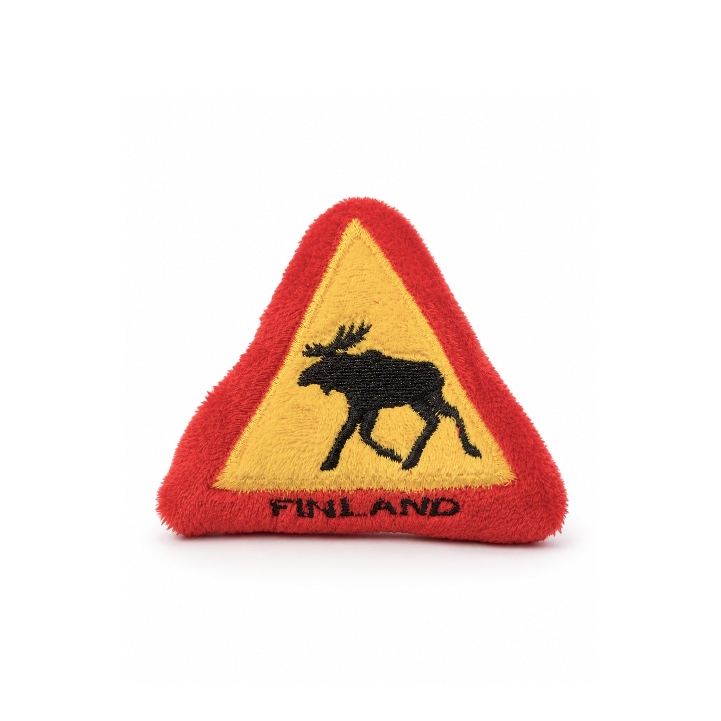 Mjuk magnet formad som en varningsskylt med en älg och texten "Finland". Magneten är fäst på ett kylskåp och kombinerar humor med en påminnelse om Finland.