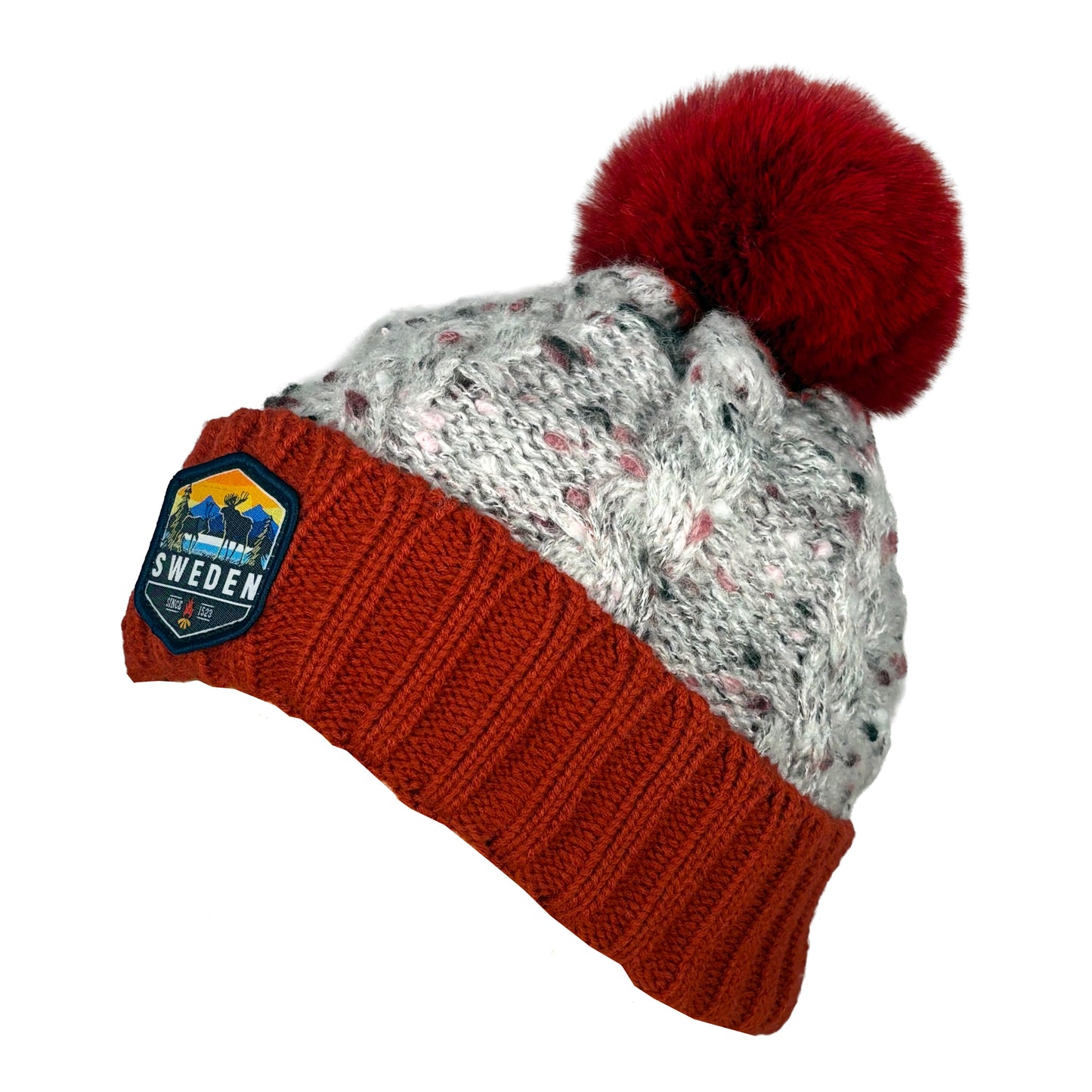Stickad mössa i rött och grått med röd tofs, röd mudd och märke med älgmotiv och texten "Sweden", sedd från sidan.