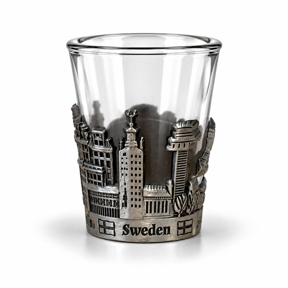 Shotsglas i glas med ett omslag i tennfärgad metall med Stockholmsmotiv och texten Sweden.