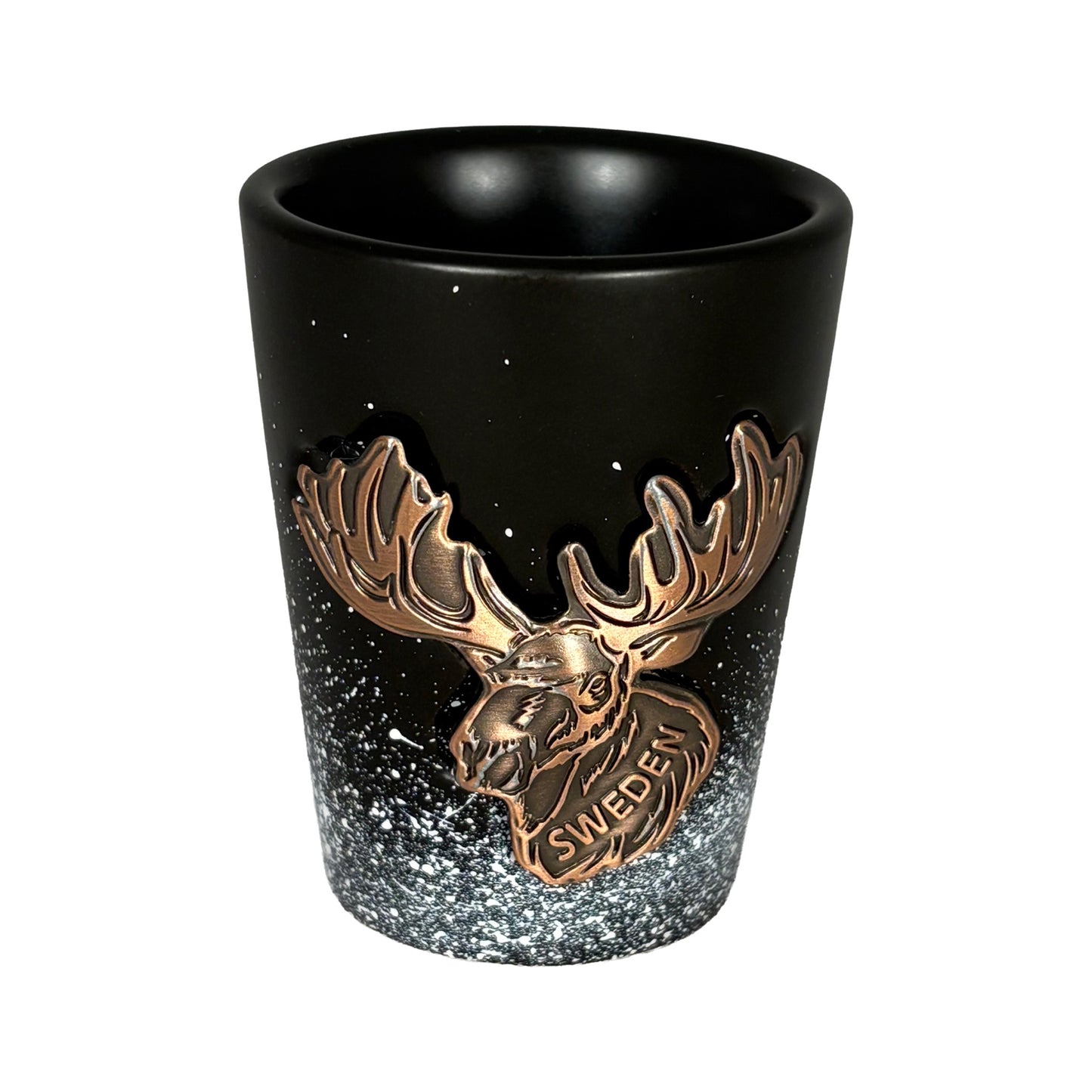 Svart shotglas med bronsfärgat älghuvud och texten "Sweden", designat med snöflingemotiv som skapar en känsla av svensk vintermagi. En elegant och rustik souvenir som symboliserar svensk natur och kultur.
