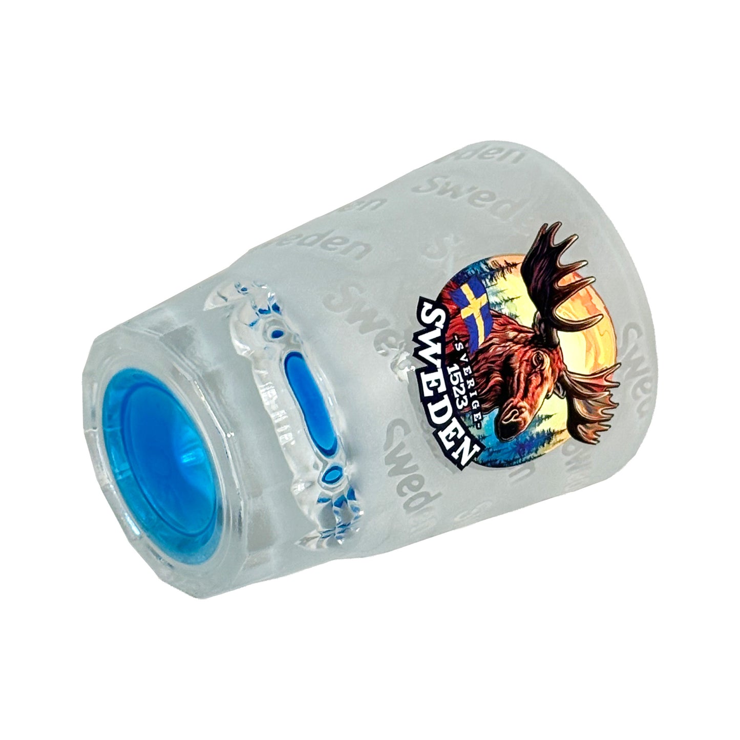Shotglas med blå botten liggande på sidan, frostat glas med älghuvud och texten "Sweden".