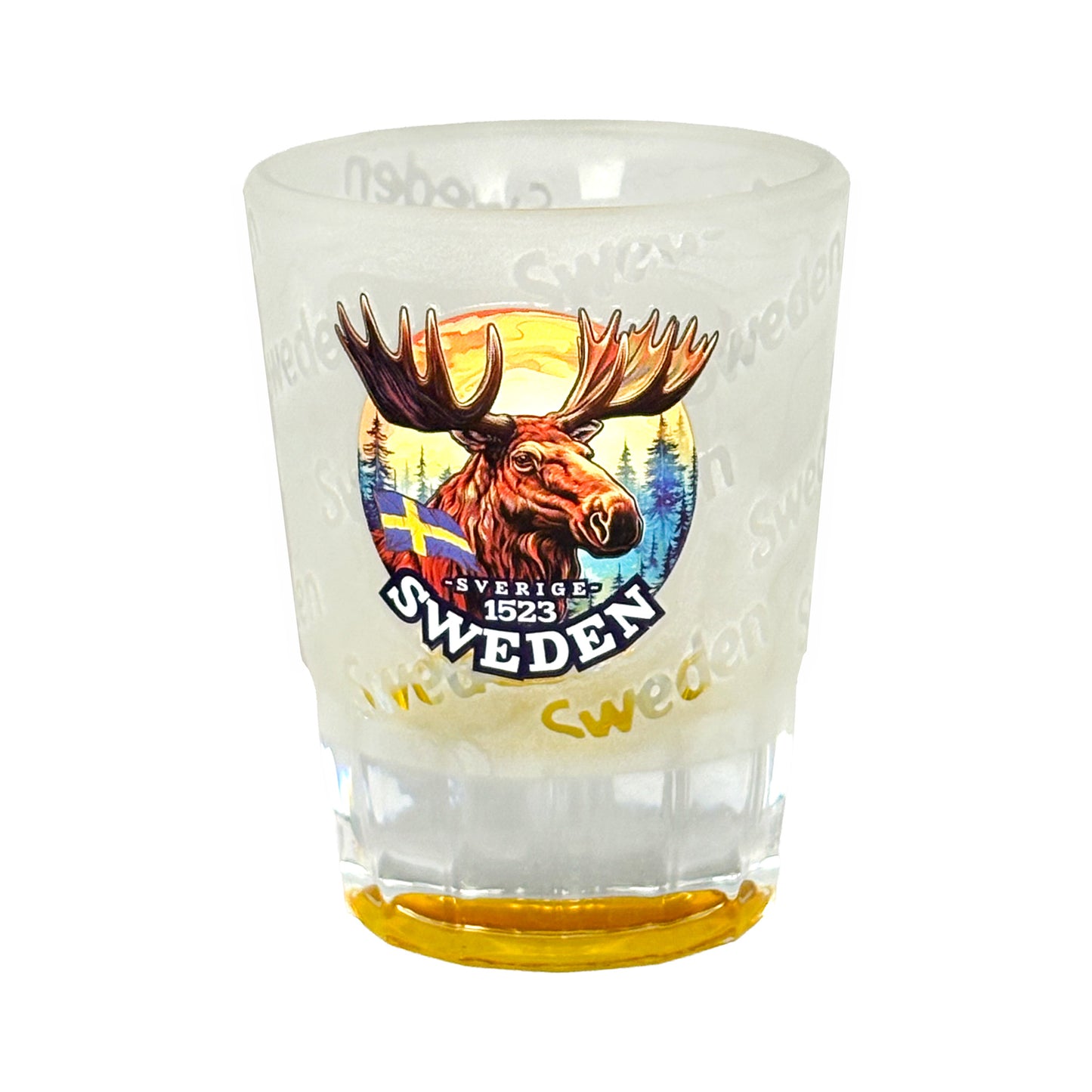 Frostat shotglas med gul botten, motiv av ett ståtligt älghuvud och texten "Sweden" flera gånger runt glaset.