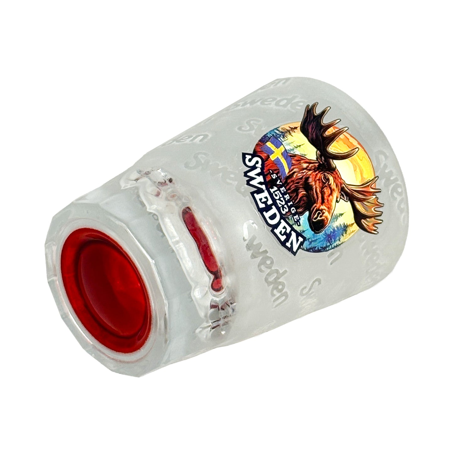 Shotglas med röd botten liggande på sidan, frostat glas med älghuvud och texten "Sweden"
