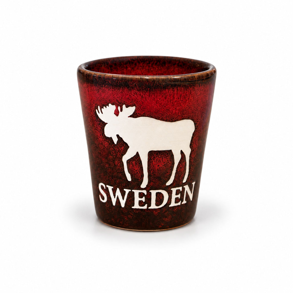 Rustikt rött shotglas med motiv av en älg och texten "Sweden", perfekt för att njuta av snaps eller shots med en svensk touch.
