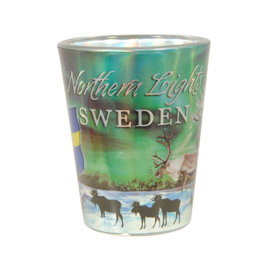 Shotglas med motiv av norrsken, texten "Northern Lights Sweden", en ren och siluetter av älgar och renar.