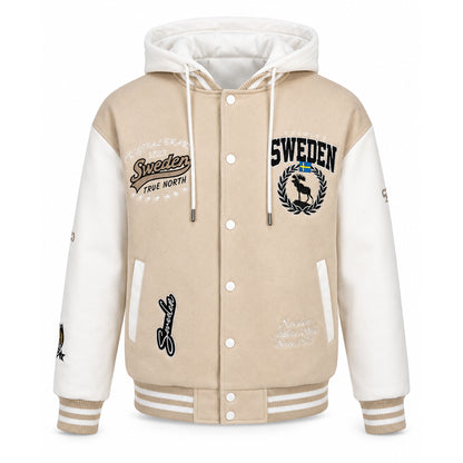 Beige och vit Sweden collage jacka med avtagbar huva, broderade Sverige-detaljer, quiltat foder och beigea muddar med vita ränder. 