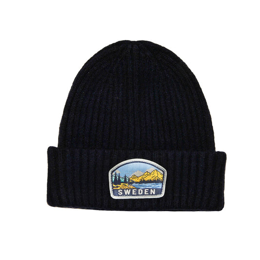 Blå stickad mössa dekorerad med ett märke med ett klassiskt svenskt motiv och texten "Sweden" framtill. 