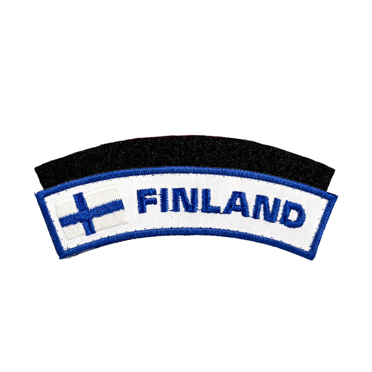 Broderat märke i vitt med blå kant, med texten “FINLAND” i blå brodyr och en finsk flagga till vänster, samt svart kardborre baksida för enkel fastsättning.