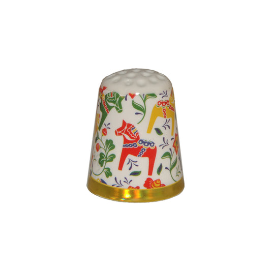 Vit fingerborg i porslin med motiv av färgglada dalahästar.