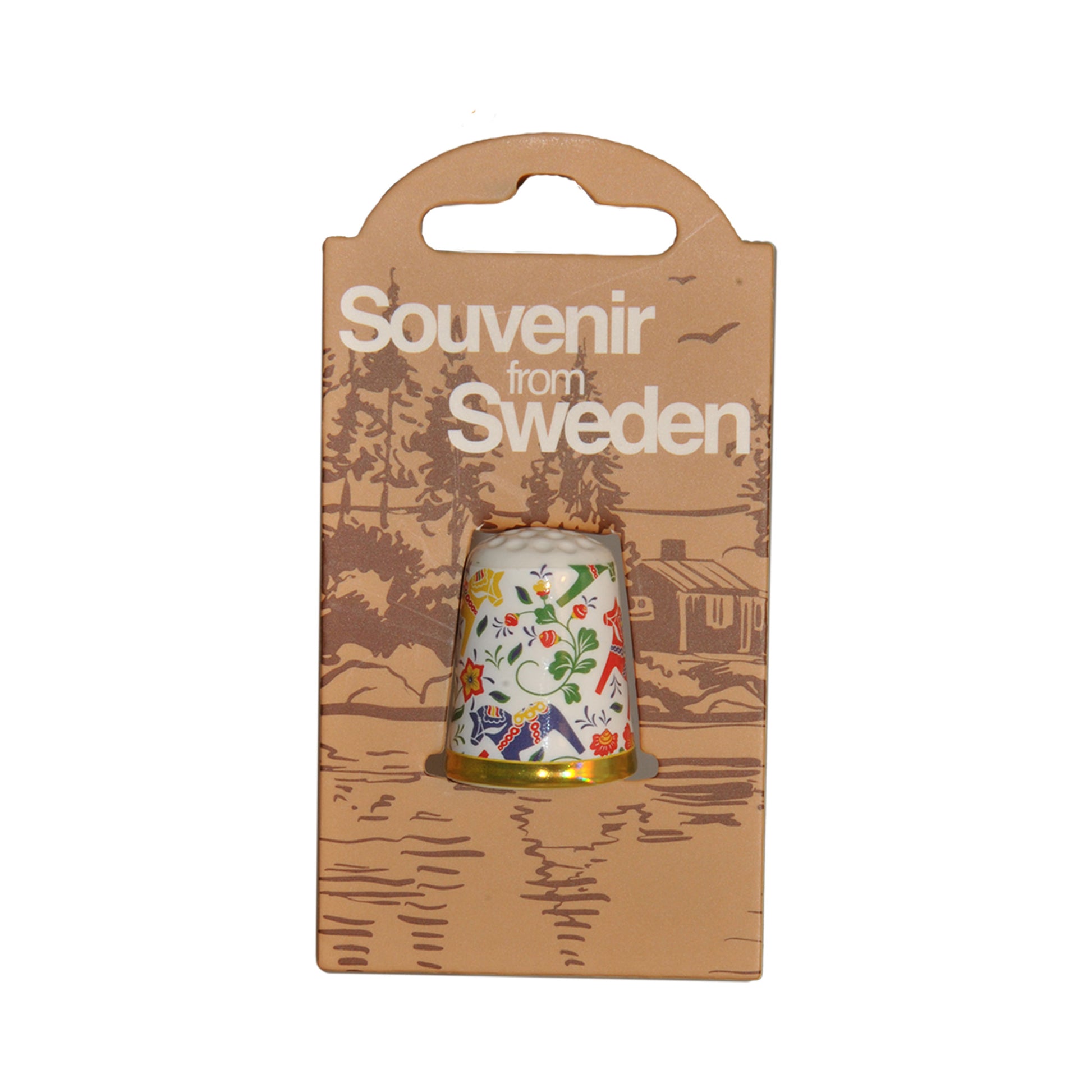 Forpackning med fingerborg med motiv av färgglada dalahästar. På förpackningen står det "Souvenir from Sweden". 