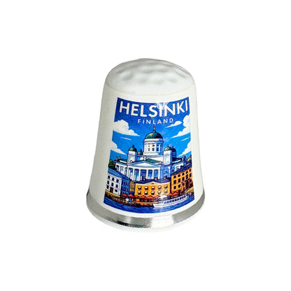 Vit fingerborg med silverkant och dekorativt motiv från Helsingfors.





