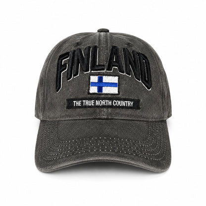 Grå vaxad keps sedd framifrån med broderad finsk flagga och texten Finland i 3D. Den vaxade ytan ger kepsen en distinkt look och känsla.