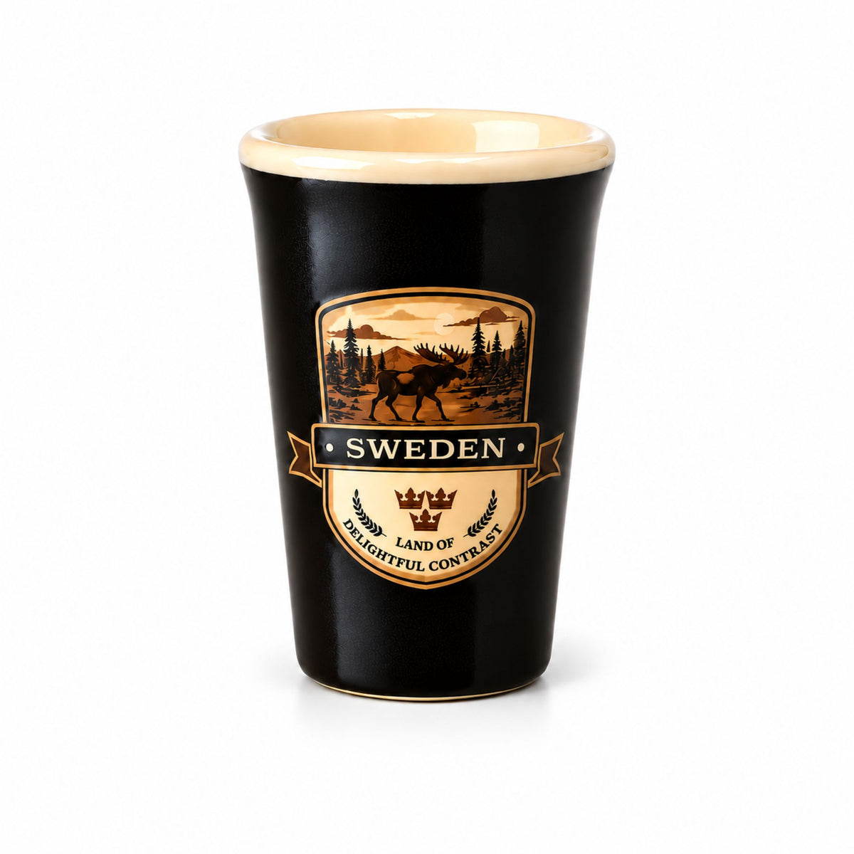 Svart shotglas med crèmefärgad insida och ett 2D-motiv av en älg i en skog, samt texten "Sweden – Land of Delightful Contrast".