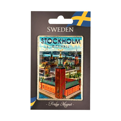 Den här magneten pryds av det ikoniska Stadshuset – en av Stockholms mest kända byggnader och hem för Nobelfesten. Magneten sitter på en grå hängettiket med texten "SWEDEN Fridge Magnet" och svensk flagga i övre hörnet.
