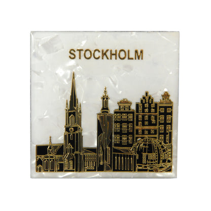 Souvenir­magnet med vit marmorering och kända byggnader från Stockholm i förgrunden.