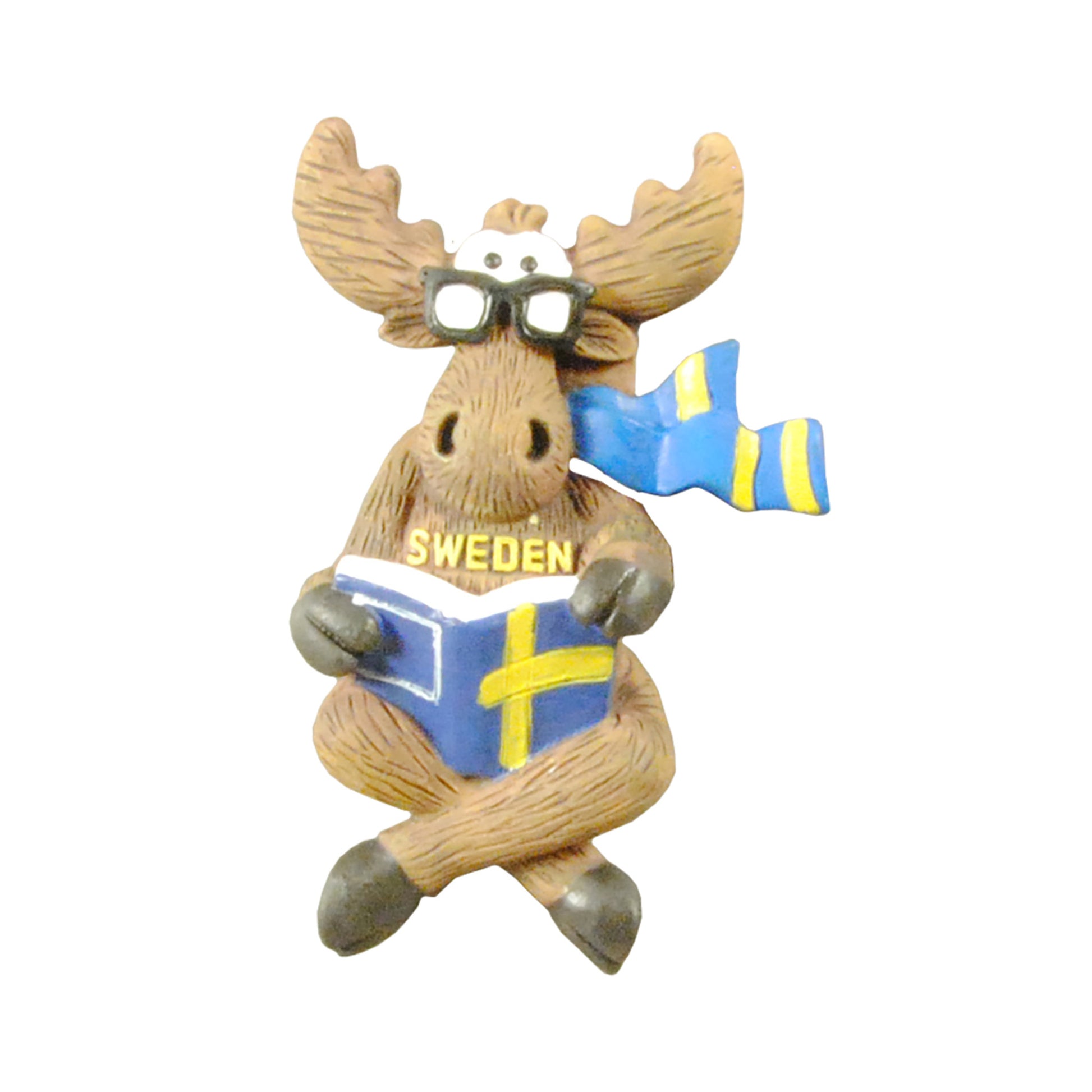 Magnet föreställande en älg med glasögon och halsduk i svenska färger, sittande med en bok med svenskt flaggomslag i knät. Texten "Sweden" finns på älgens bröst. En charmig och lekfull souvenir.
