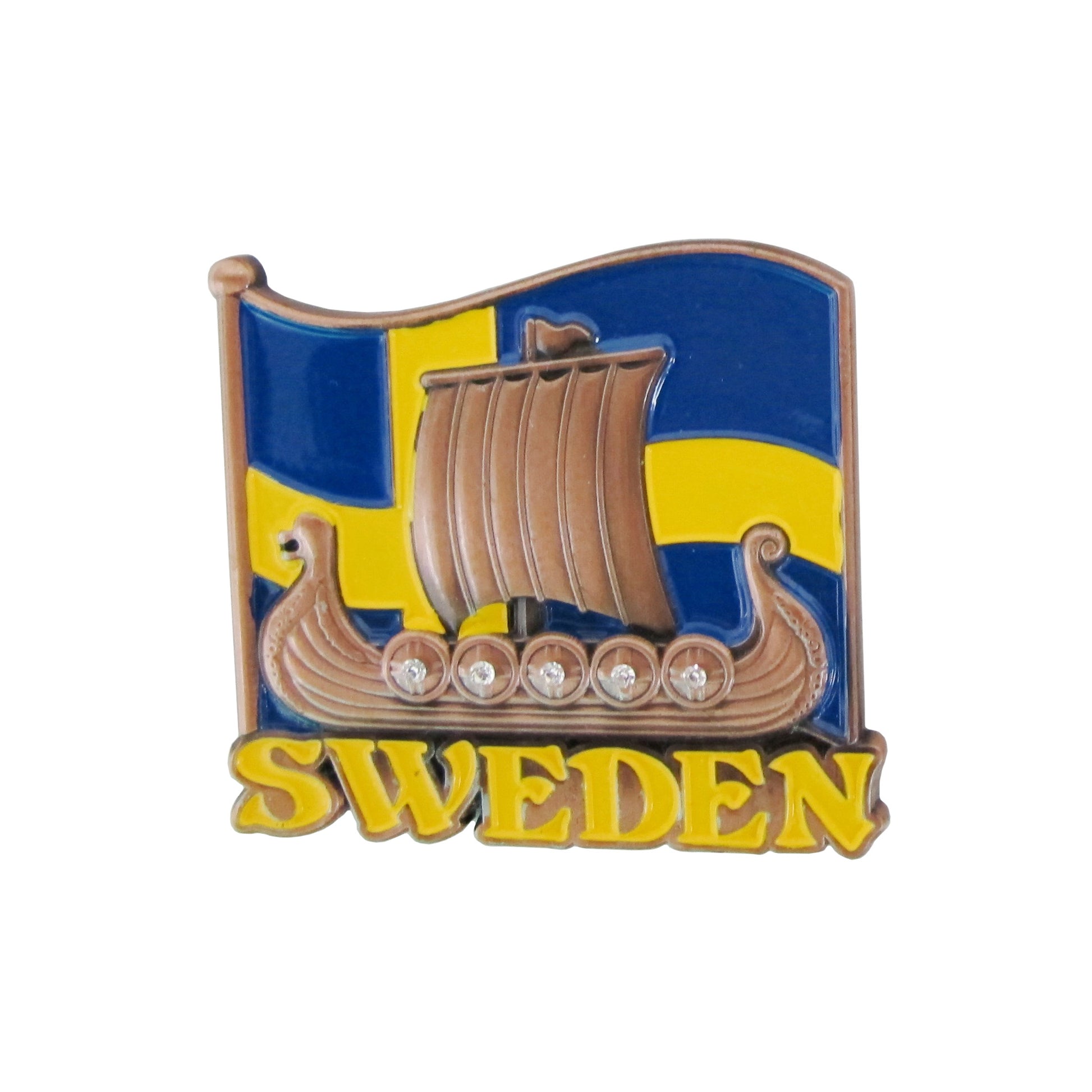 Bild på metallmagnet med vikingaskepp i 2D och svenska flaggan i bakgrunden. Vikingaskeppet är i bronsfärg med dekorativa stenar på sköldarna