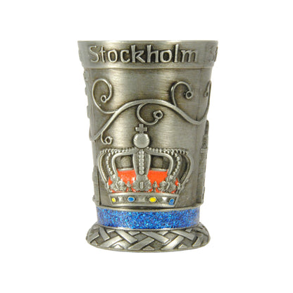 Metallshotglas med blå glitterkristaller och motiv i relief av en kunglig krona – ett av tre motiv på samma glas.