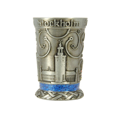 Metallshotglas med blå glitterkristaller och motiv i relief av Stadshuset – ett av tre motiv på glaset.