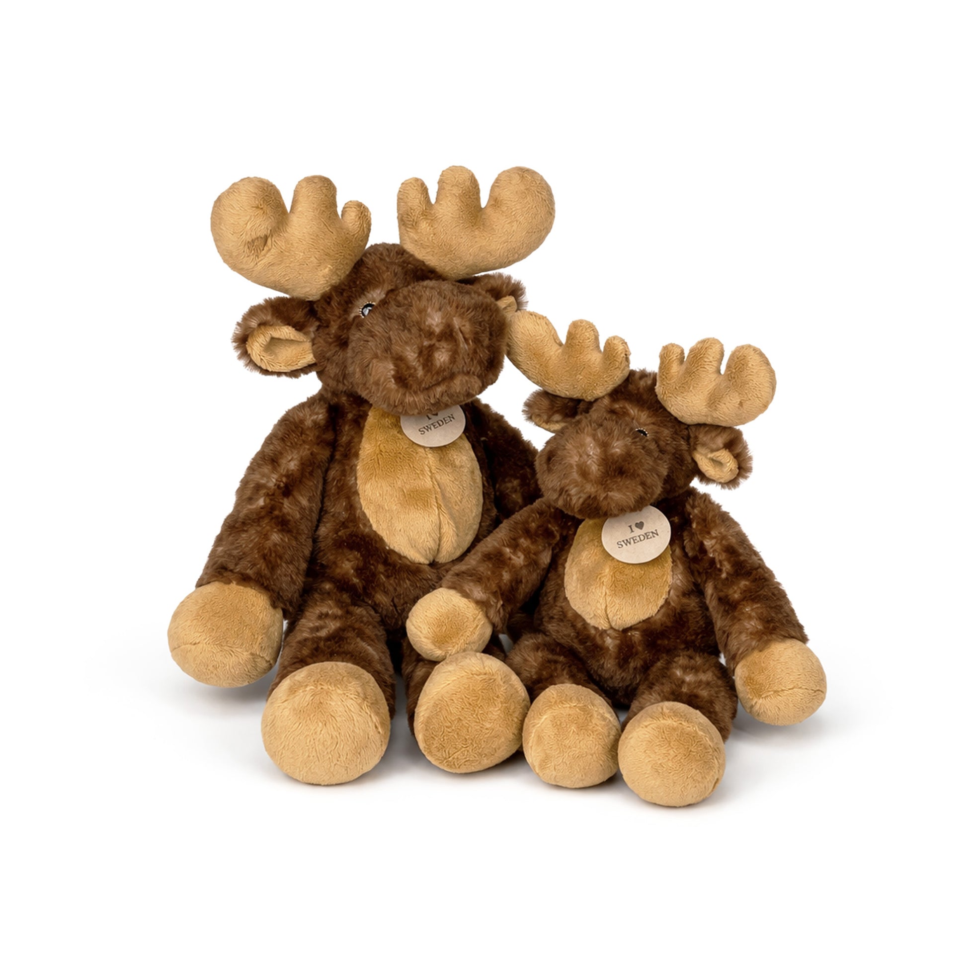 Två gosedjursälgar i olika storlekar (27 cm och 35 cm) sittande tillsammans, med mjuk brun päls, långa ben och ‘I ♥ Sweden’-detalj – lekfulla och kramgoa leksaker med nordisk charm.