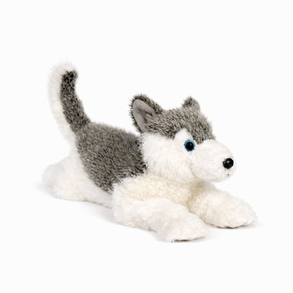Grå/vit liggande gosedjurs husky med blåa ögon, sedd snett framifrån.