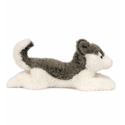 Grå/vit liggande gosedjurs husky med blåa ögon, sedd från sidan.