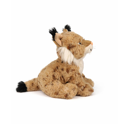 Beige sittande gosedjurs lodjur med bruna prickar och svarta tofsar på öronen, sedd från sidan.