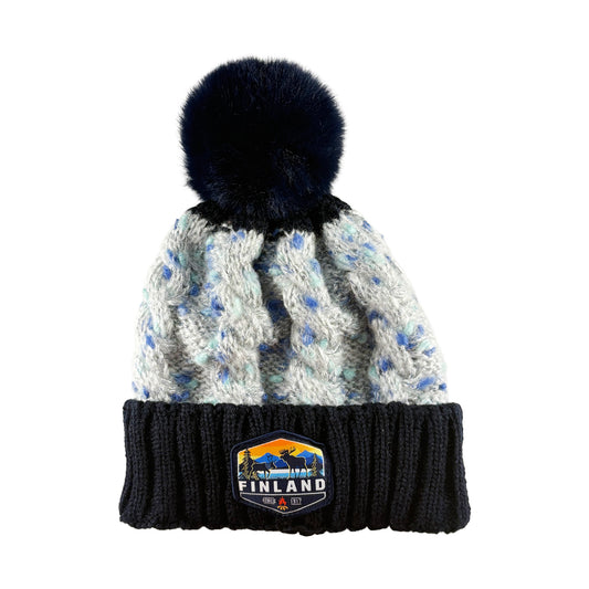 Stickad mössa med blå tofs och märke med texten Finland på mudden - sedd framifrån. 