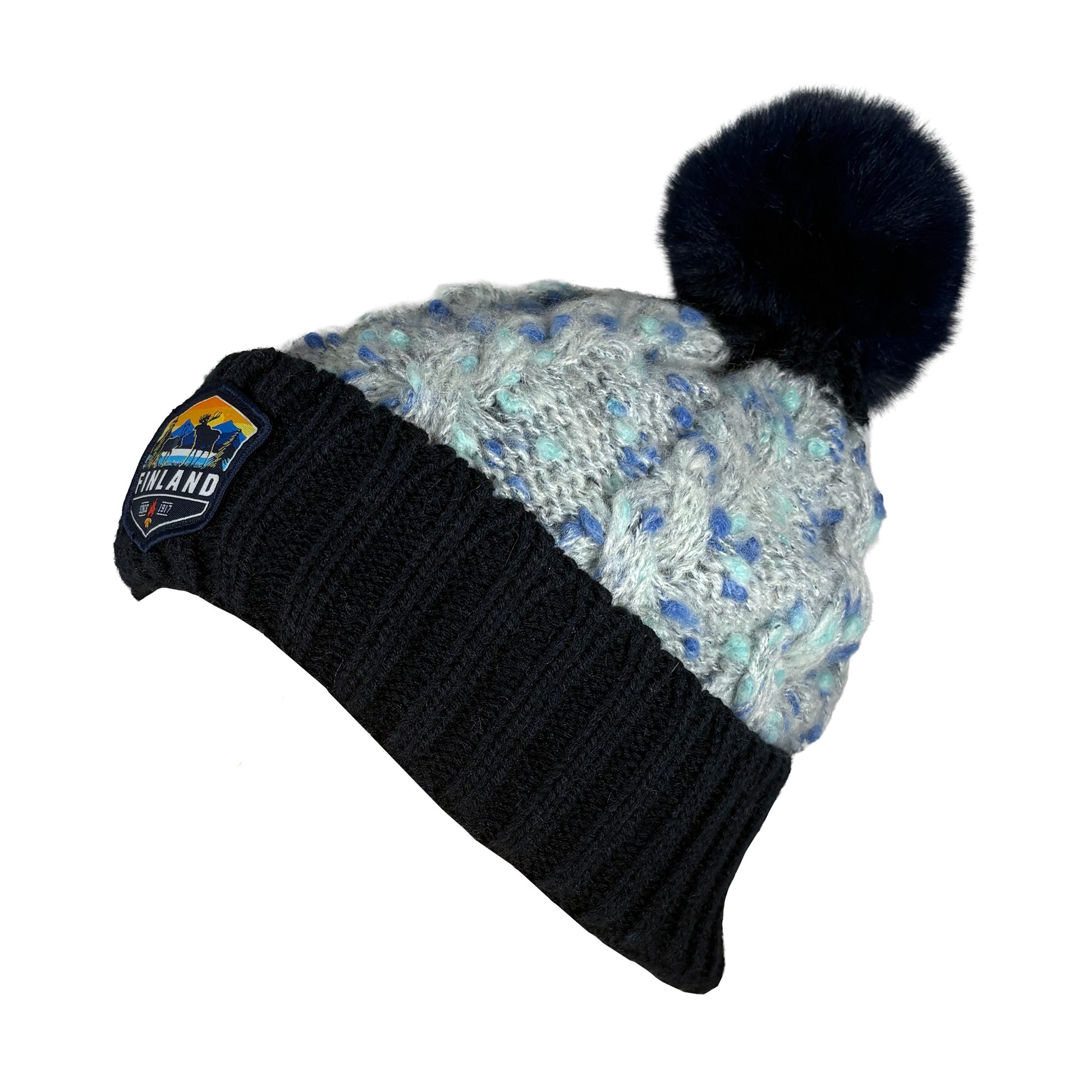 Stickad mössa med blå tofs och märke med texten Finland på mudden - sedd från sidan.