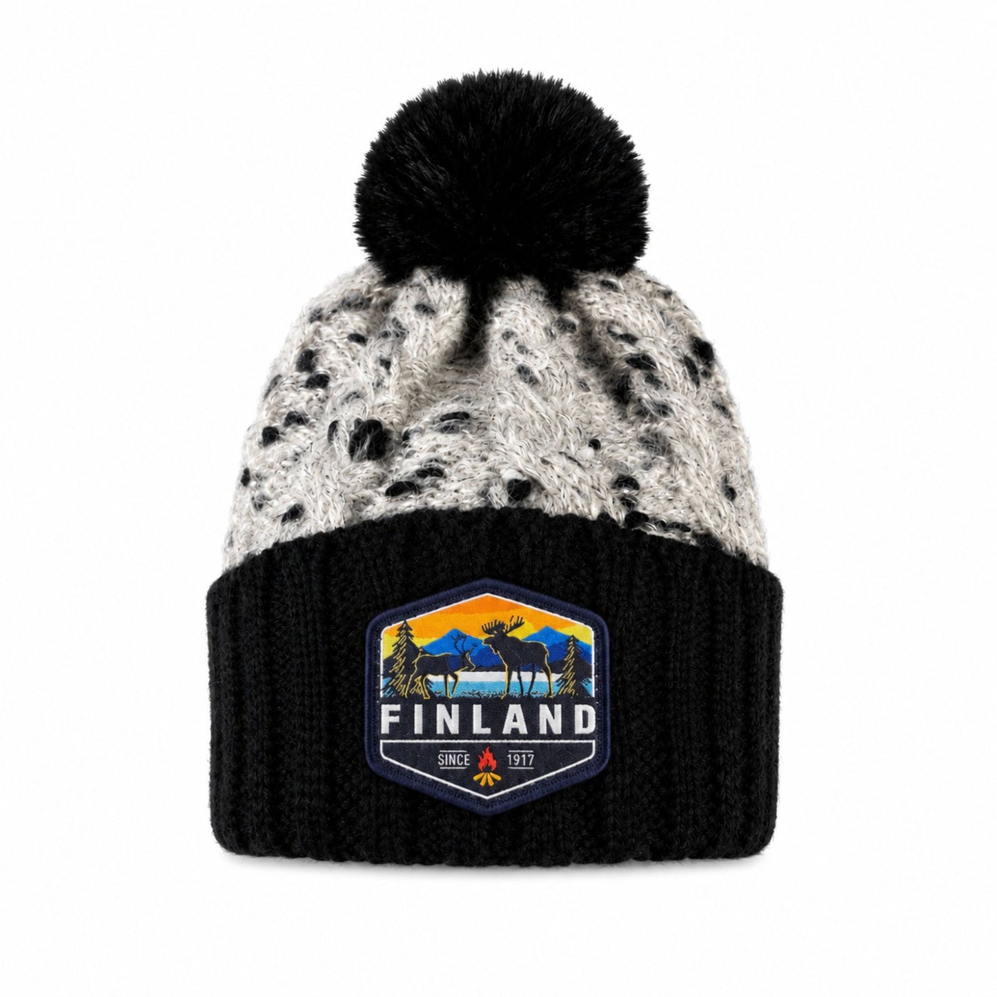 Stickad svart mössa med svart tofs och märke med texten Finland på mudden - sedd framifrån. 