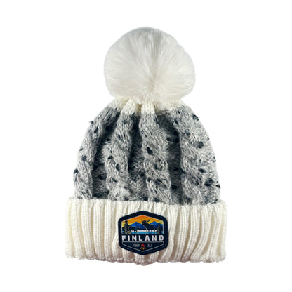 Souvenirmössa från Finland – stickad modell i vitt och grått med vit tofs och muddmärke - sedd framifrån. 