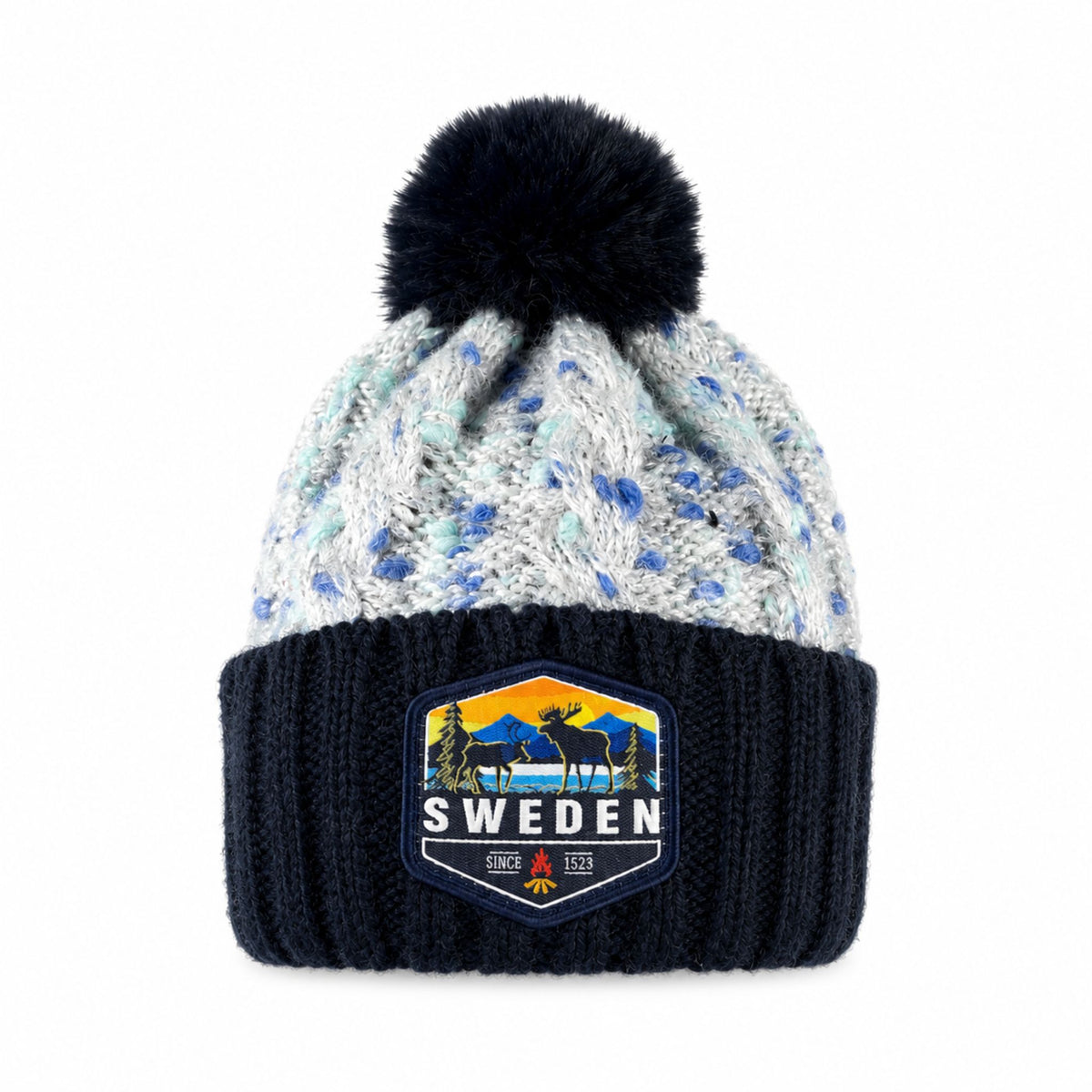Stickad mössa i blått och grått med blå tofs, sedd framifrån. Märke med älgmotiv och texten "Sweden" synligt på mudden.