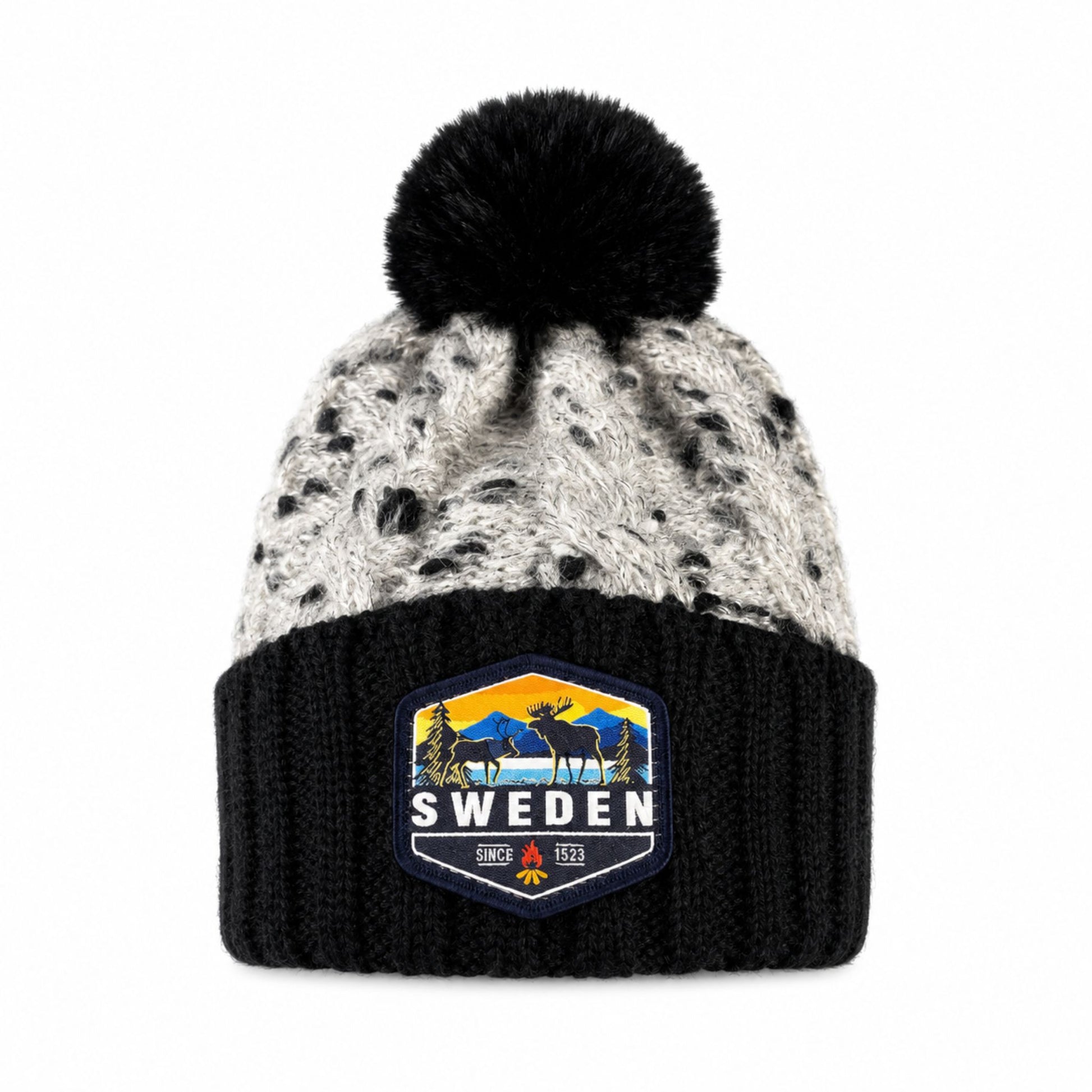 Stickad mössa i svart och grått med svart tofs, sedd framifrån. Älgmärke med texten "Sweden" synligt på mudden.