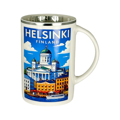Vit mugg med silverkant och Helsingforsmotiv, sedd framifrån med handtaget åt höger – texten "Helsinki" skymtar inuti.