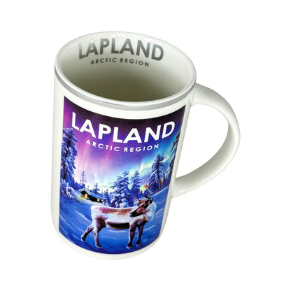Vit mugg sedd snett uppifrån, visar silverfärgad text "Lapland Artic Region" på insidan.