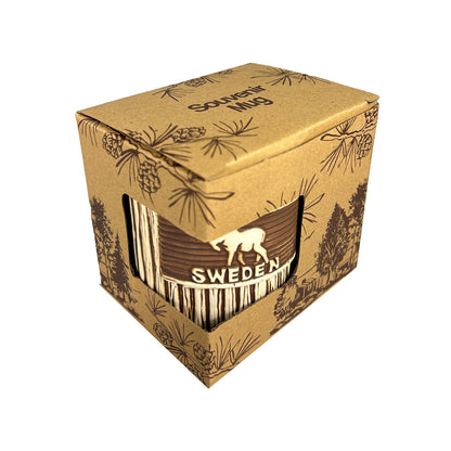 Mugg med älg och texten "SWEDEN" med träliknande utseende. Visas här snett ovanifrån i förpackning, mörkbrun kartong med skogsmotiv och text “Souvenir Mug” på locket.