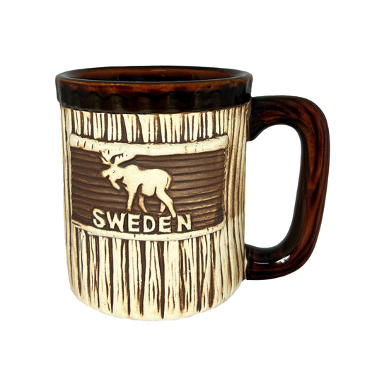 Mugg med älg och texten "SWEDEN". Den här muggen har ett träliknande utseende med handtag och kant upptill i mörkbrunt. 