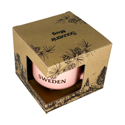 Aprikosfärgad mugg i brun kartong med texten "Souvenir Mug" på toppen, sedd snett uppifrån.