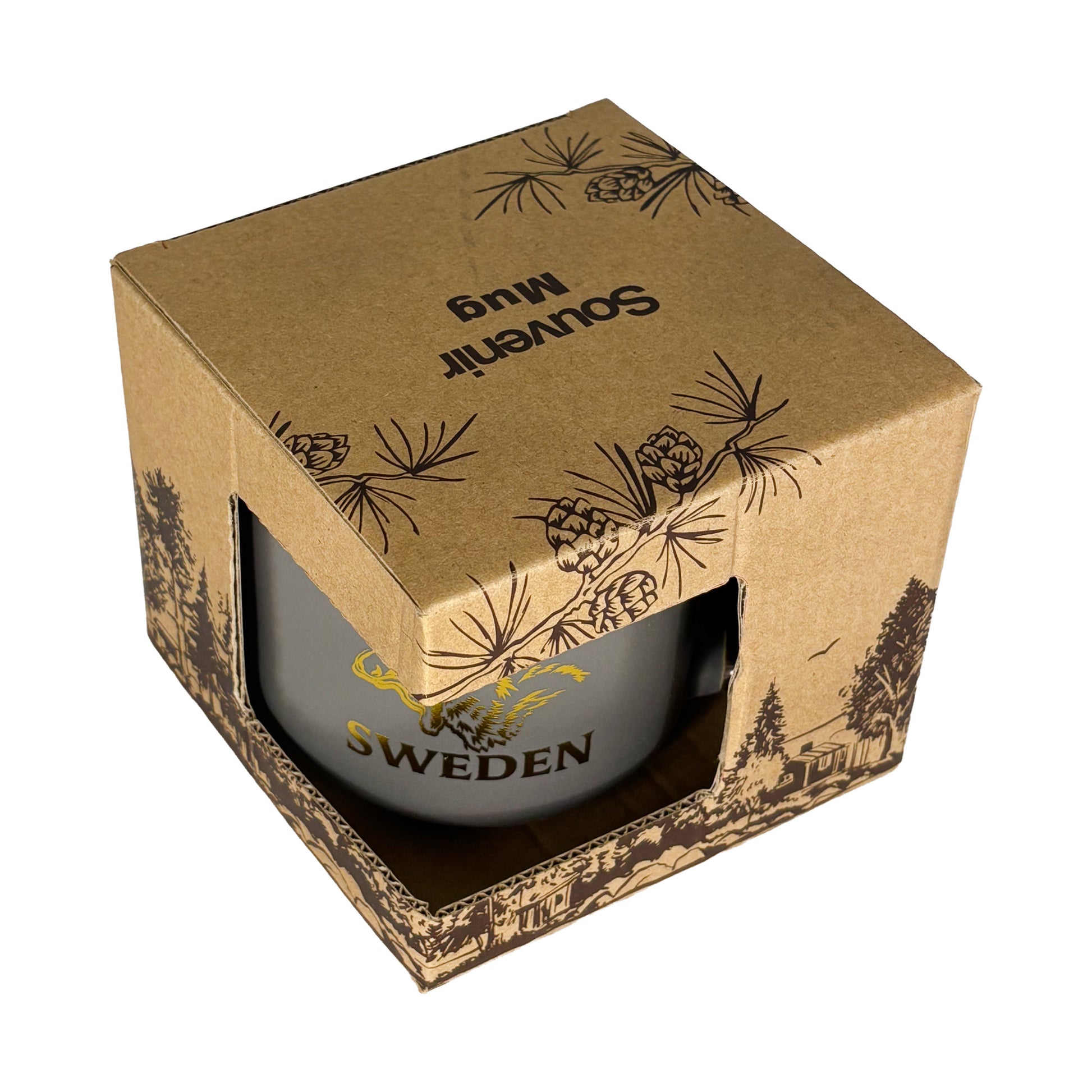 Muggen i förpackning sedd snett uppifrån – texten "Souvenir Mug" syns på toppen av lådan.