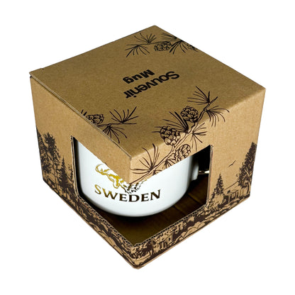 Muggen i förpackning sedd snett uppifrån med texten "Souvenir Mug" synlig på toppen.