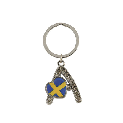 Metallnyckelring med bokstaven A. Bokstaven är dekorerad med glitterstenar. På bokstaven finns även ett hjärta med en svensk flagga. 