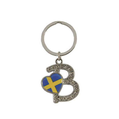 Metallnyckelring med bokstaven B. Bokstaven är dekorerad med glitterstenar. På bokstaven finns även ett hjärta med en svensk flagga. 