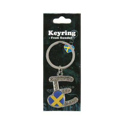 Metallnyckelring med bokstaven E. Bokstaven är dekorerad med glitterstenar. På bokstaven finns även ett hjärta med en svensk flagga. Visas här i sin förpackning. Svart förpackning med  texten "Keyring från Sweden" i vitt.