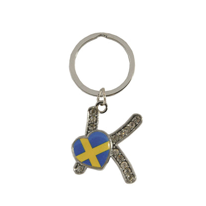 Metallnyckelring med bokstaven K. Bokstaven är dekorerad med glitterstenar. På bokstaven finns även ett hjärta med en svensk flagga.