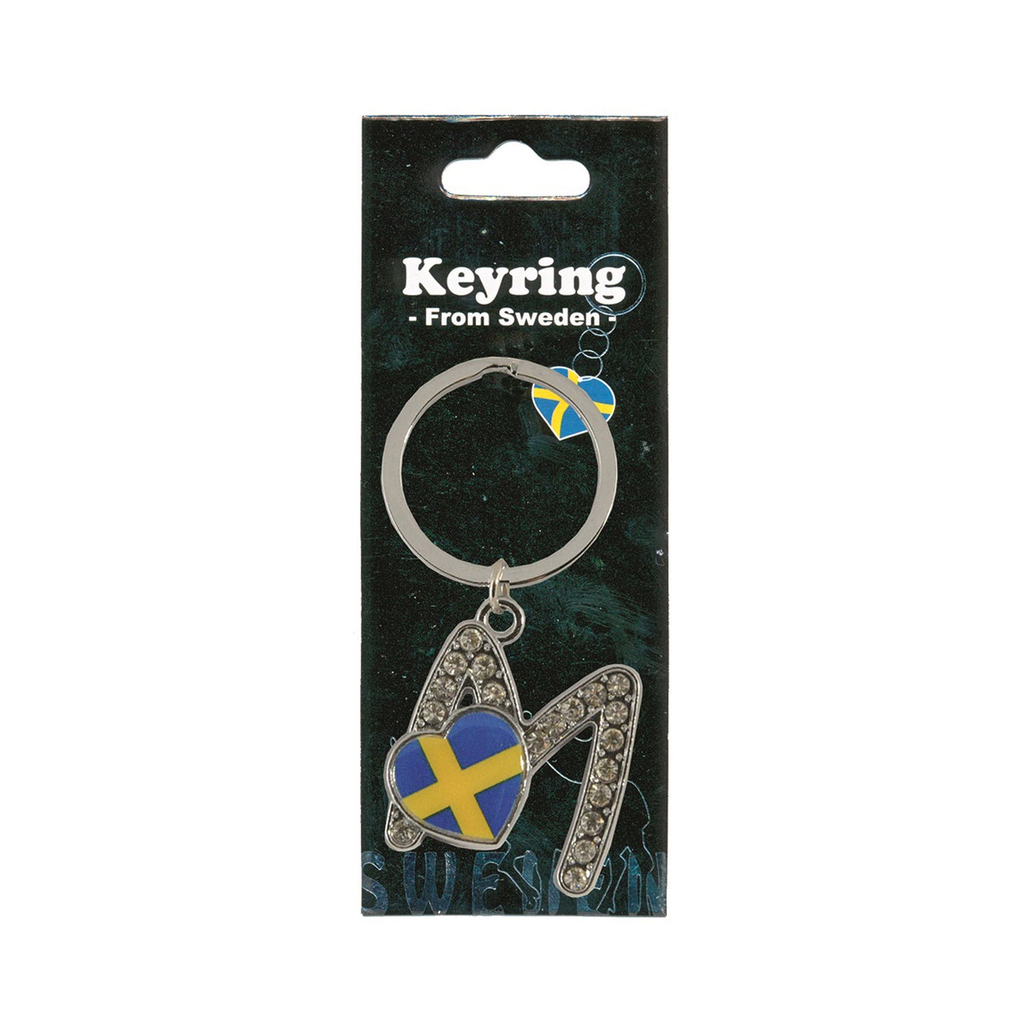 Metallnyckelring med bokstaven M. Bokstaven är dekorerad med glitterstenar. På bokstaven finns även ett hjärta med en svensk flagga. Visas här i sin förpackning. Svart förpackning med  texten "Keyring från Sweden" i vitt.