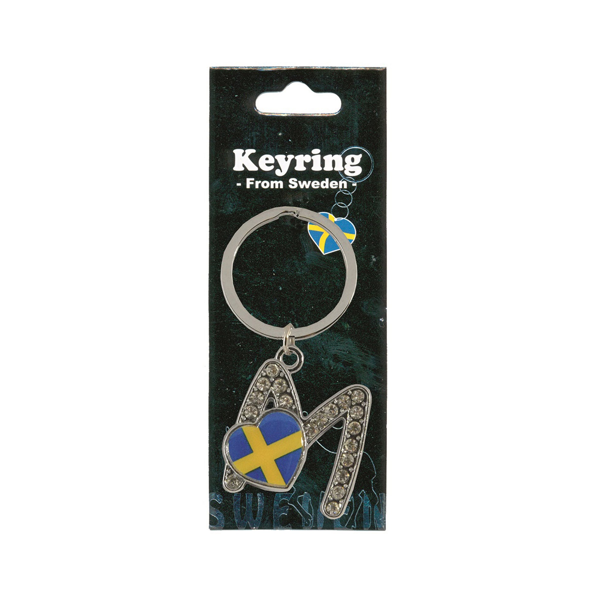 Metallnyckelring med bokstaven M. Bokstaven är dekorerad med glitterstenar. På bokstaven finns även ett hjärta med en svensk flagga. Visas här i sin förpackning. Svart förpackning med  texten "Keyring från Sweden" i vitt.